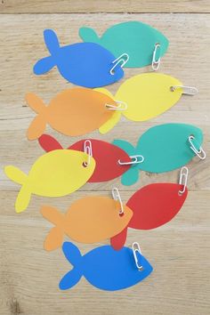 several fish shaped paper clips on a wooden surface