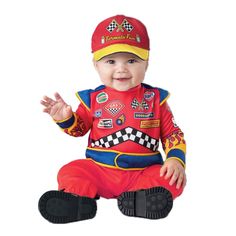 a baby sitting on the ground wearing a red and yellow outfit with patches, smiling