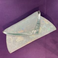 Release your inner 1980s diva with this simply stunning silver clutch or shoulder bag by Van Dal, perfect to lend a touch of vintage glamour and style to any outfit.  It is made from a foil abstract patterned printed suede that shines in rainbow colours in the light and is trimmed in silver leather. It has an asymmetric shaped flap with a stud fastening and an optional, detachable shoulder strap inside or can be used as a clutch. The roomy interior is fully lined with black Van Dal satin jacquar Vintage Silver Clutch For Events, Elegant Iridescent Bags, Metallic Clutch Evening Bag For Parties, Silver Envelope Evening Bag, Silver Rectangular Clutch For Celebration, Formal Silver Envelope Evening Bag, Silver Envelope Evening Bag For Party, Silver Clutch, Rainbow Colours