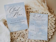 the wedding stationery is laid out on top of a doily with some feathers