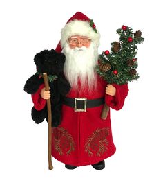 a santa claus figurine holding a christmas tree and two black poinsettis