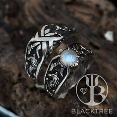 a silver ring with a white stone in the center on top of a tree branch