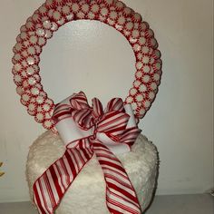 a white cake with red and white candy canes on it's top, sitting in front of a wall