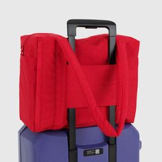 two pieces of luggage are stacked on top of each other, one red and the other blue