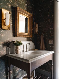 a bathroom sink sitting under a mirror next to a wall mounted faucet with flowers on it