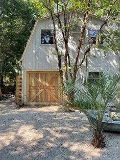 a boat is parked in front of a white barn with a wooden door and window