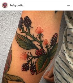 a close up of a person's arm with flowers and leaves tattooed on it