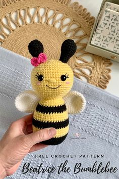 a crocheted bee with a pink flower in it's hair sitting on top of a table