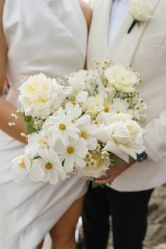 the bride and groom are holding white flowers