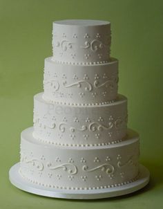 a three tiered white wedding cake sitting on top of a green tablecloth covered table