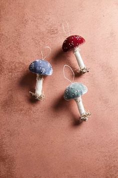 three different colored mushrooms sitting on top of a pink floor next to eachother