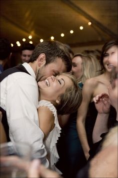 a man and woman kissing in front of a group of people