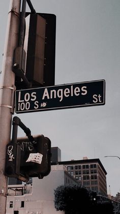 a street sign on the corner of los angeles and 10th st, with buildings in the background