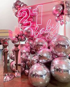 pink and silver balloons are on display in front of a sign that says 21 baby