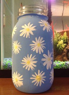 a blue jar with white daisies painted on it