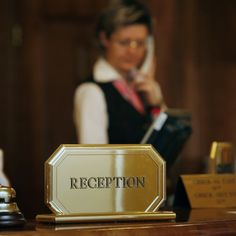 a woman is talking on the phone in front of a reception sign that says reception