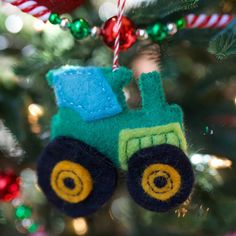 a christmas ornament hanging from the tree with a toy truck on it's side