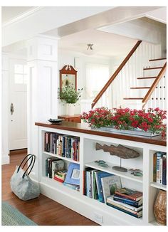 a book shelf filled with lots of books next to a stair case covered in flowers