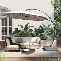 an outdoor living area with couches, tables and umbrellas