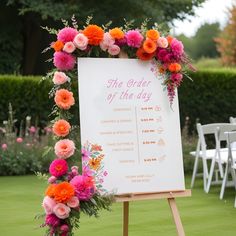 a sign with flowers on it sitting in the middle of a field next to chairs