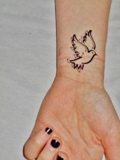 a woman's wrist tattoo with a bird on it