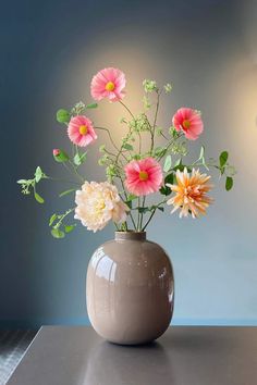 a vase filled with lots of flowers on top of a table next to a wall