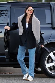 a woman is walking her dog in front of a vehicle