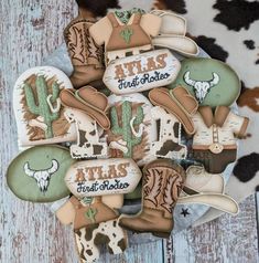 cookies decorated with cowboy boots and hats are arranged on a plate in front of a cow print rug