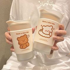 two people holding up coffee cups with cartoon drawings on the lids and bottom one has a teddy bear on it