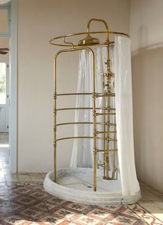 a bathroom with a gold shower and white curtains