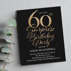 a black and gold 60th surprise birthday party card next to a green leafy plant