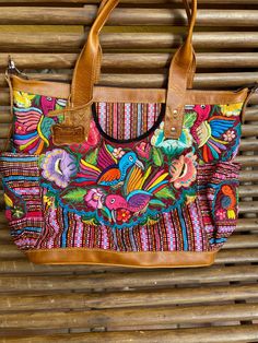 A stunning happy and unique piece that will add charm and beauty to any traveling . Leather and a beautiful handmade Huipil Weaved on a backstrap loom, it takes more than six months to complete one and is a unique piece that will add color and style to any wardrobe , A huipil is a women's blouse worn by Mayan women from Guatemala. Each handmade Huipil its unique since it depends on the inspiration of the weaver. Size inches wide 19 X tall 14 inches wide 6 inches depth 5 metal feet at the bottom Brown Embroidered Shoulder Bag For Vacation, Embroidered Brown Shoulder Bag For Vacation, Bohemian Tote Weekender Bag For Everyday Use, Brown Fair Trade Shoulder Bag For Travel, Traditional Tote Weekender Bag For Everyday Use, Fair Trade Brown Shoulder Bag For Travel, Bohemian Weekender Tote Bag For Daily Use, Brown Bohemian Weekender Bag For Travel, Bohemian Fair Trade Shoulder Bag For Everyday Use