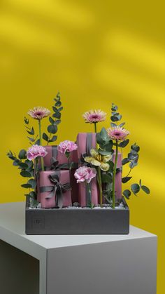 a bunch of wrapped presents sitting on top of a table next to flowers and greenery