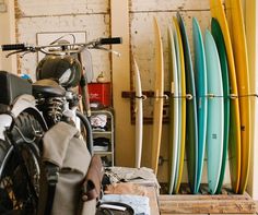 several surfboards are lined up against the wall in a shop with two bikes parked next to them