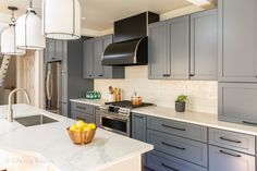 a kitchen with gray cabinets and marble counter tops