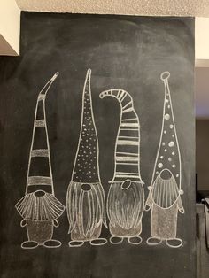 a chalkboard drawing of three gnomes standing next to each other