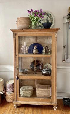 a wooden shelf with plates and vases on top of it in a living room