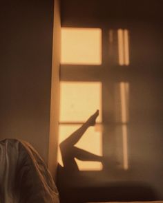 the shadow of a person laying on a bed in front of a window