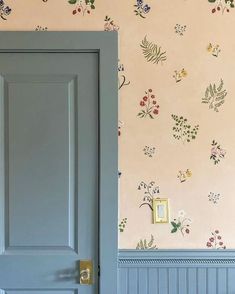 an open door in a room with floral wallpaper on the walls and blue painted doors