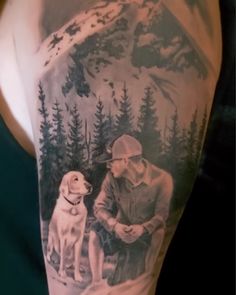 a man with a dog on his arm is next to a mountain and forest scene