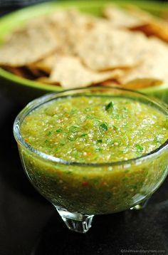 a bowl of guacamole with tortilla chips in the back ground