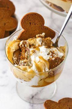 an ice cream sundae in a glass bowl with two heart shaped cookies on the side