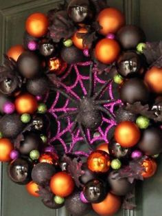 an orange and black christmas ornament hanging on a green door with purple accents