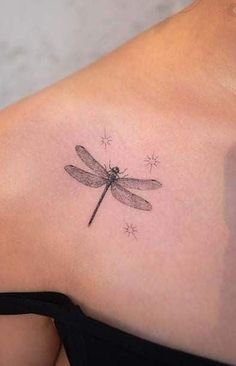 a woman's back shoulder with a dragonfly tattoo on it