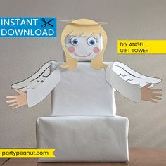 an angel made out of paper sitting on top of a table next to a box