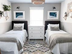 two beds in a room with pictures on the wall above them and a rug underneath them