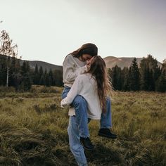 two people are hugging in the middle of a field