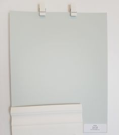 there is a white wall with two pegs on it and a light green paint color