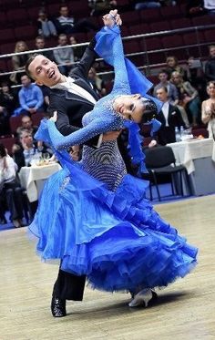 two people in blue dresses dancing on a dance floor