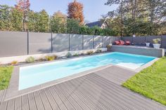 an empty swimming pool in the middle of a backyard with wooden decking and fence